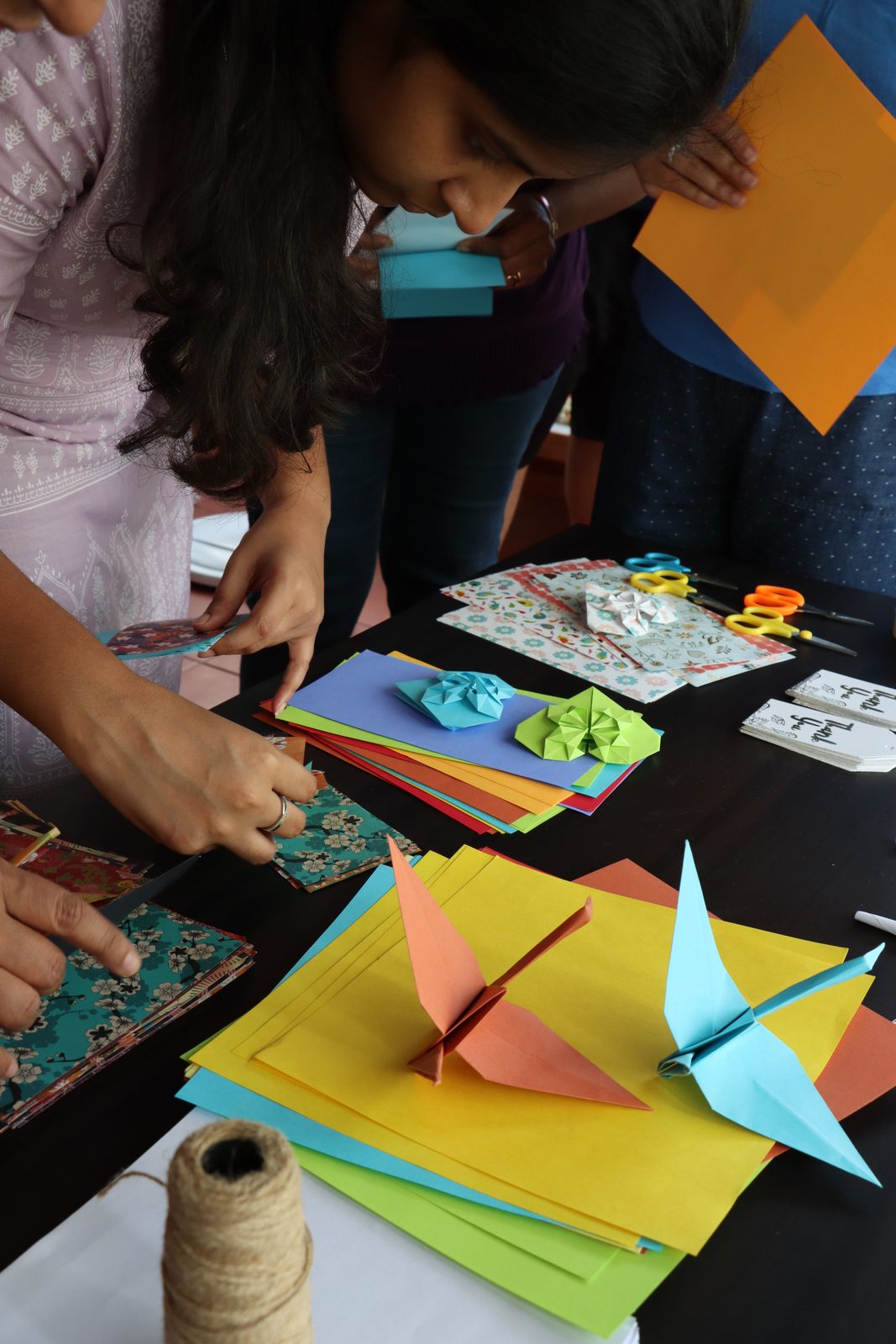 Participants folding origami cranes with coloured paper